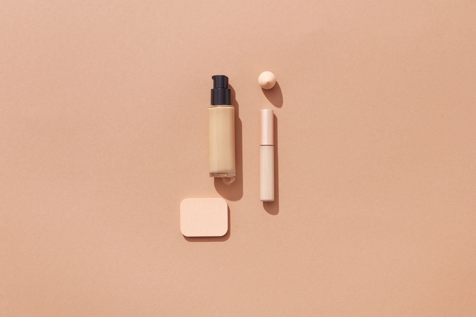 Flat lay of beauty products on a warm brown background with space for text.